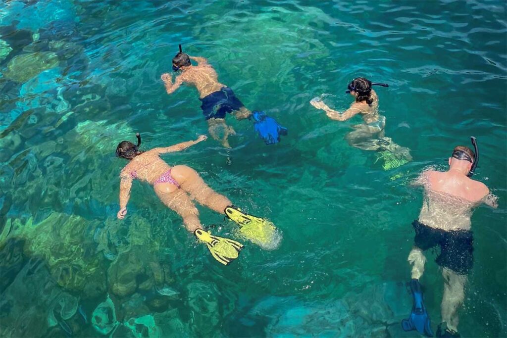 Tourists snorkeling in clear turquoise water during a Phu Quoc island hopping and snorkeling boat tour