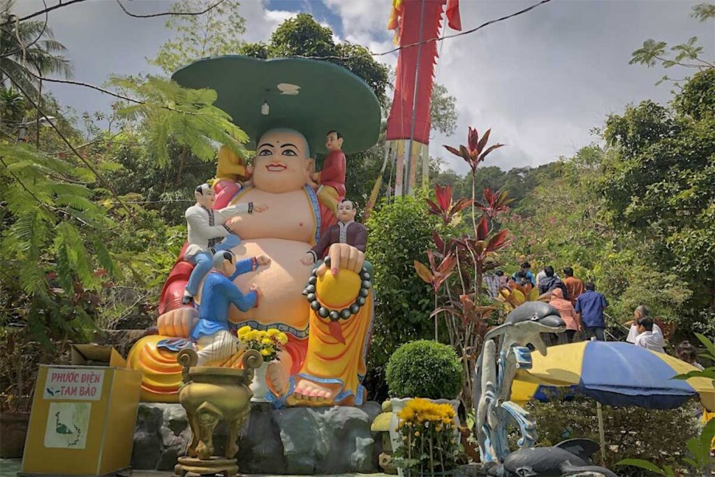 Large laughing Buddha statue at Su Muon Pagoda Phu Quoc surrounded by smaller figures and garden setting