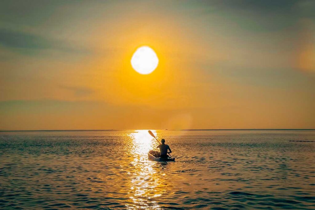 Person kayaking during sunset in Phu Quoc with golden sunlight reflecting across the calm sea
