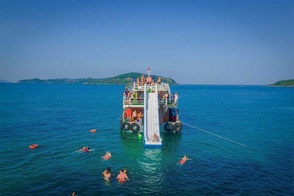 Travelers swimming from a group boat tour in Phu Quoc with a large water slide in the clear sea near the southern islands