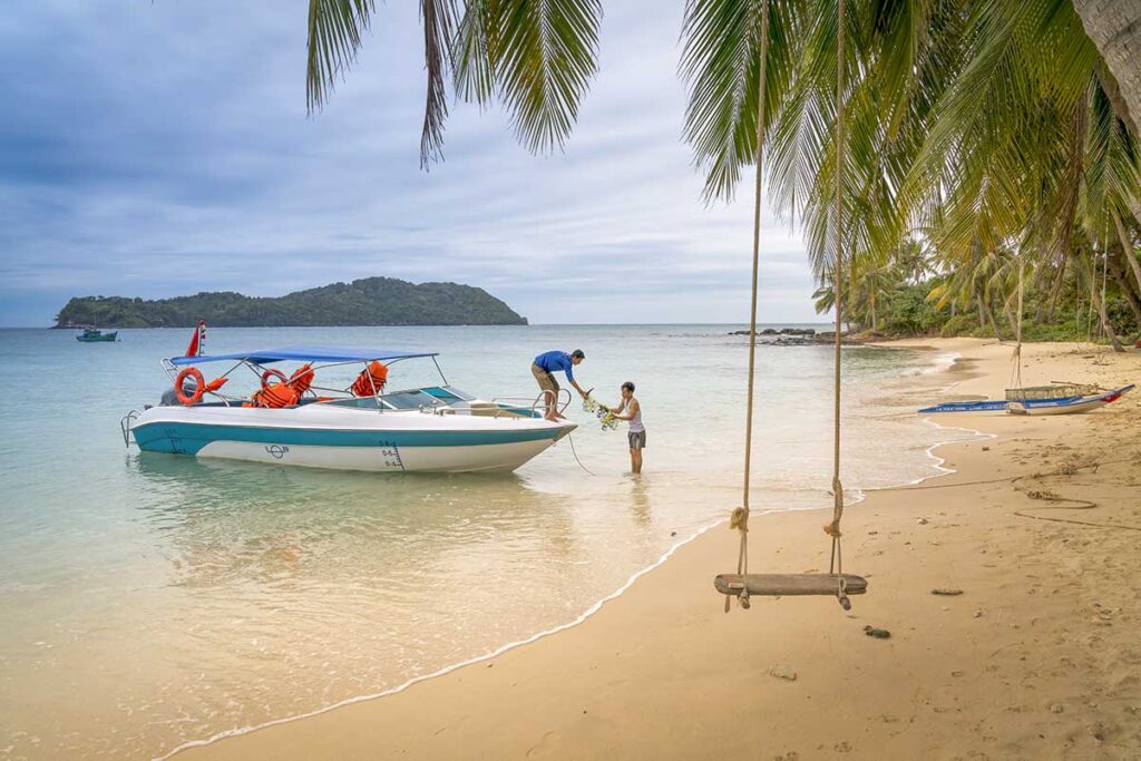 Speedboat arriving at a quiet tropical beach during a Phu Quoc island hopping tour with palm trees and a beach swing