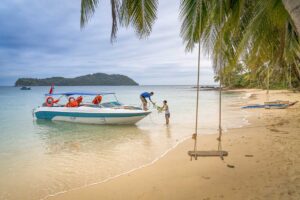 Speedboat arriving at a quiet tropical beach during a Phu Quoc island hopping tour with palm trees and a beach swing