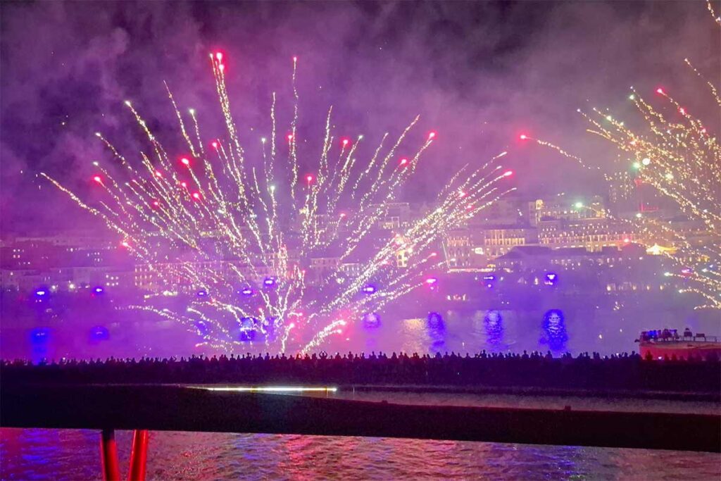 Symphony of the Sea Phu Quoc fireworks display seen from Kiss Bridge with bright sparks and smoke over the sea and Sunset Town skyline