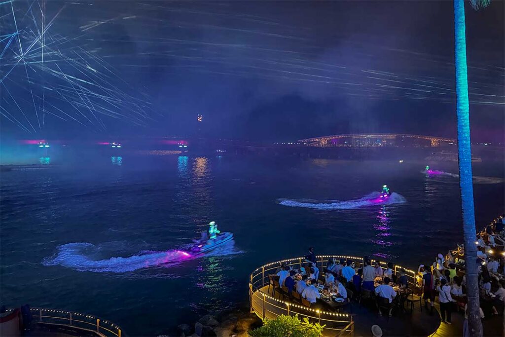 Symphony of the Sea Phu Quoc jetski performance viewed from Sun Bavaria GastroPub with riders creating colorful trails on the water and guests dining nearby