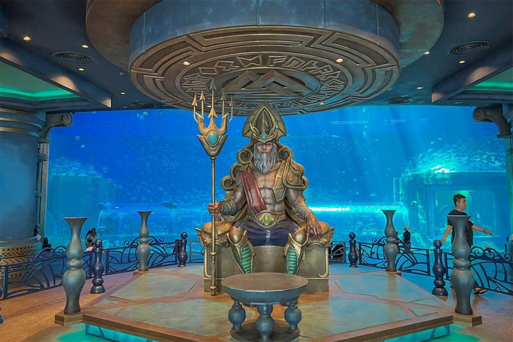 Underwater themed aquarium hall inside VinWonders Phu Quoc with giant sea king statue and large fish tanks