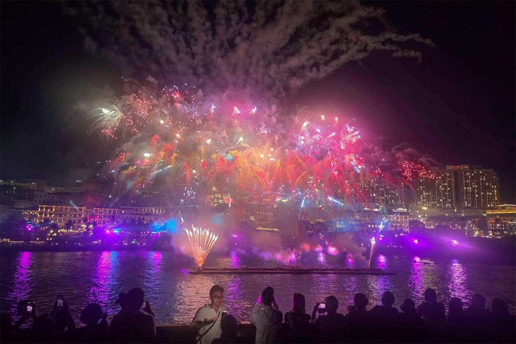 Visitors watching Symphony of the Sea Phu Quoc fireworks from Kiss Bridge with colorful explosions reflecting on the water