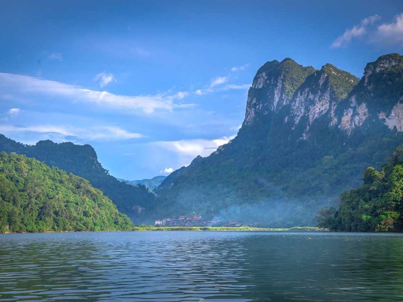 View over Ba Be Lake with far in distance a small village and a huge mountain behind that