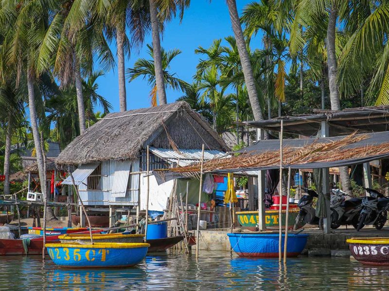 Colorful round basket boats lined up along the riverbank in Cam Thanh Village near Hoi An, ready for coconut forest tours.
