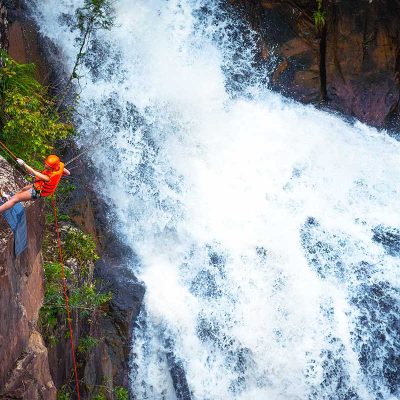 A man abseiling down a cliff next to a waterfall as part of canyoning in Dalat.