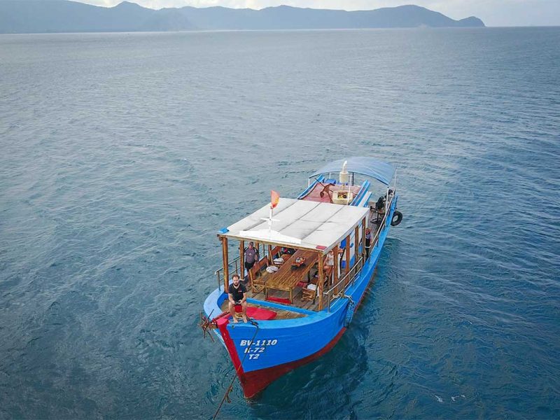 A drone view of a diving boat near Con Dao, floating over the turquoise waters, surrounded by the island’s stunning marine environment.