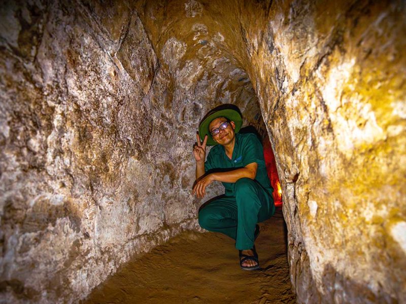 cu chi tunnels 1 A local tour guide kneeling down inside the Cu Chi Tunnels, one of the best things to do in Vietnam.