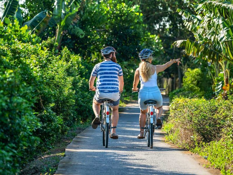 A tourist couple is doing cycling in the Mekong Delta of the countryside of Cai Be