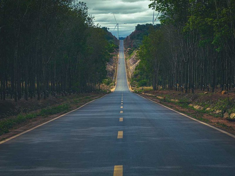 A seemingly endless straight road cutting through the dense forest of Dak Lak, offering a scenic and remote journey.