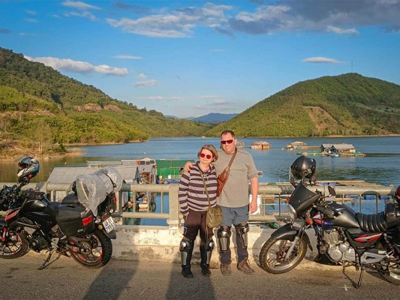 Couple stopping at a scenic lake during a Dalat Nha Trang Easy Rider tour, riding motorbikes through the Central Highlands