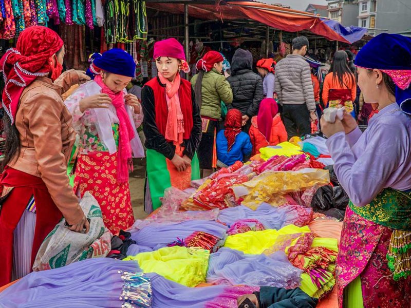 Colourful ethnic woman browsing clothes at the Dong Van Market