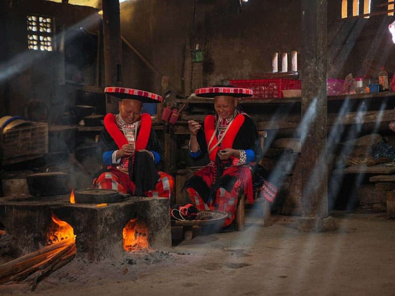 ethnic minority cao bang Two Red Dao ethnic minority woman inside a house cooking on an open fire in Cao Bang