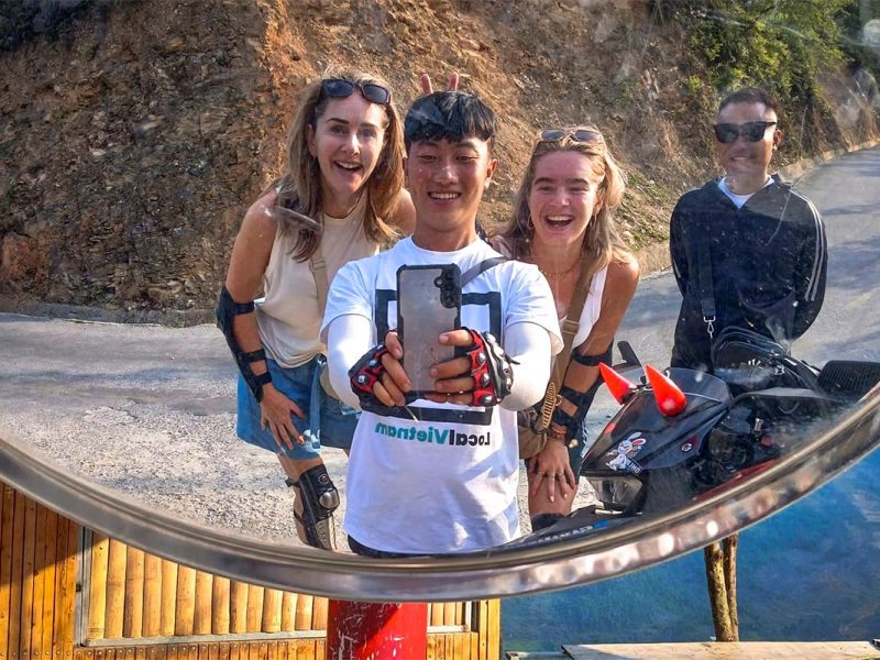 Local Vietnam Easy Rider guide taking a mirror selfie with guests during a Ha Giang Loop motorbike tour, showing real interaction between guides and travelers on the road