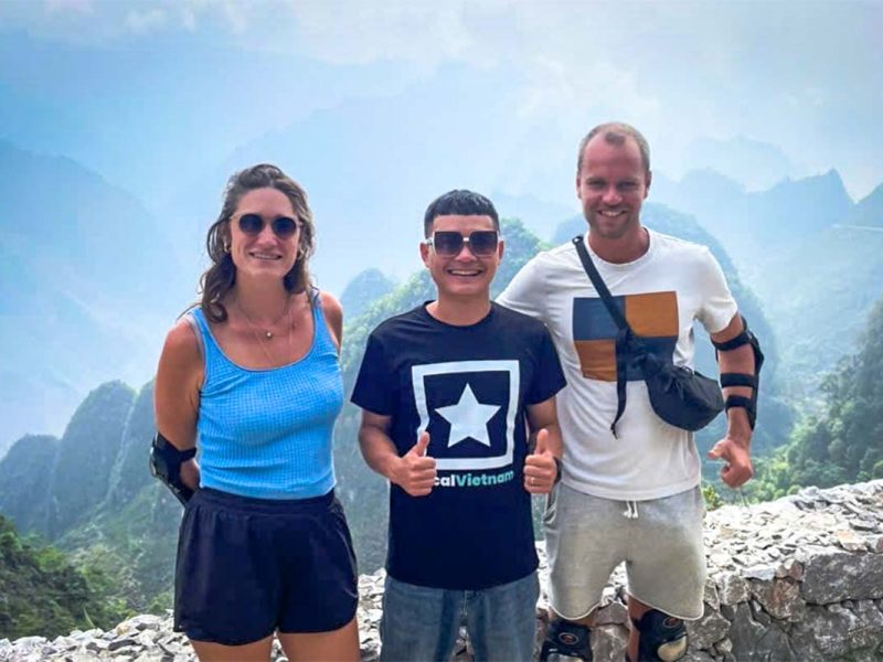 Local Vietnam guide with guests on a Ha Giang Loop Easy Rider tour, standing at a scenic mountain pass reached during a guided motorbike itinerary