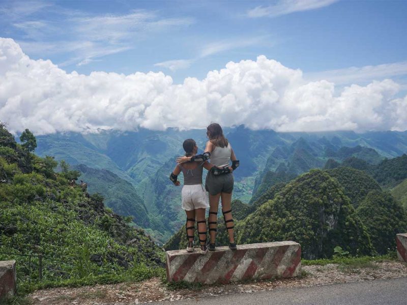 Two women in motorbike gear posing with mountain views during Ha Giang motorbike tour