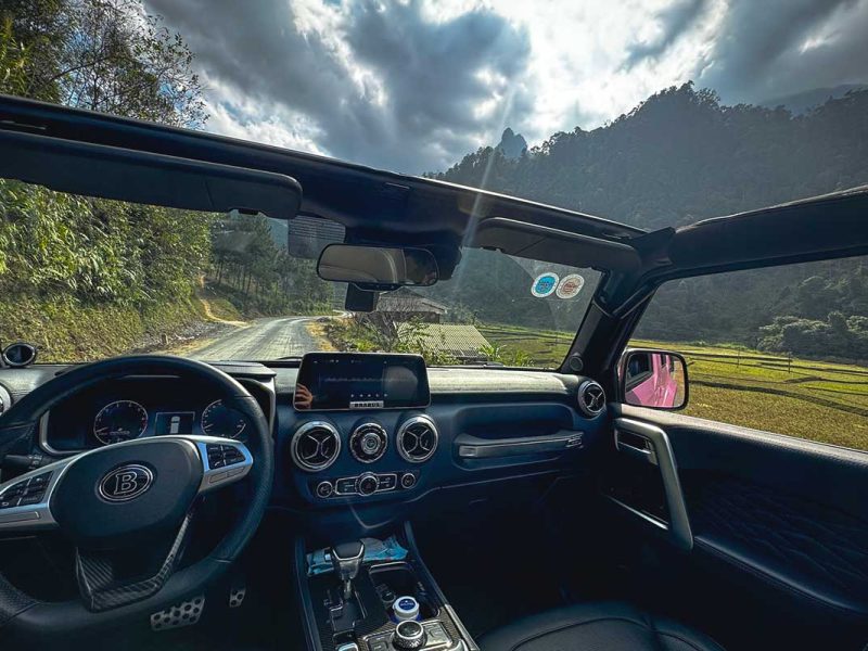 View from inside a modern open jeep during a Ha Giang Loop tour through the mountains