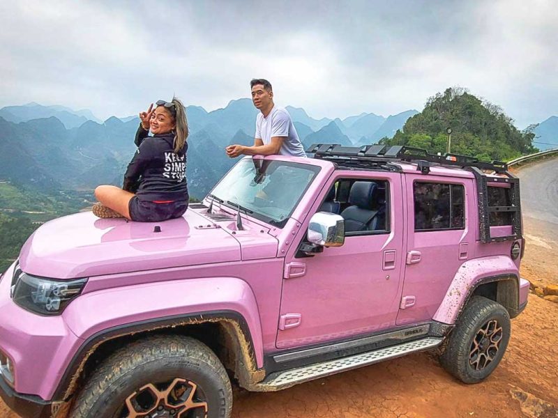Tourist couple enjoying Ha Giang mountain views from modern jeep with open roof