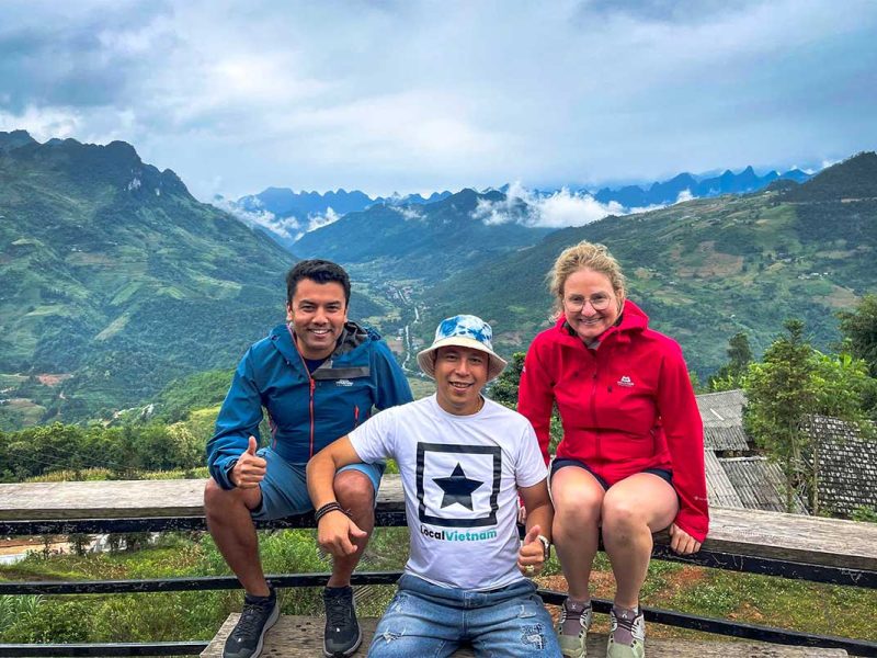Local Vietnam guide with travelers during a Ha Giang Loop tour, enjoying panoramic mountain views along the route