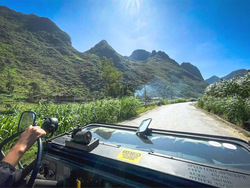 View from inside a military jeep driving along a scenic mountain road in Ha Giang