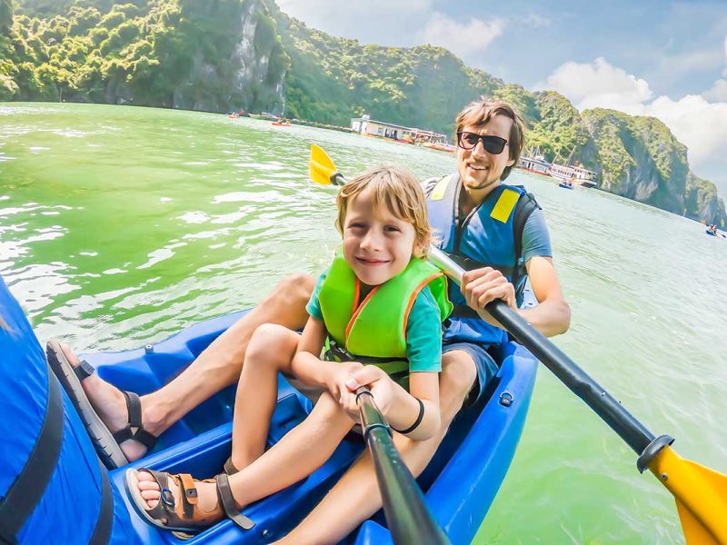 A man and his son are kayaking in Halong Bay