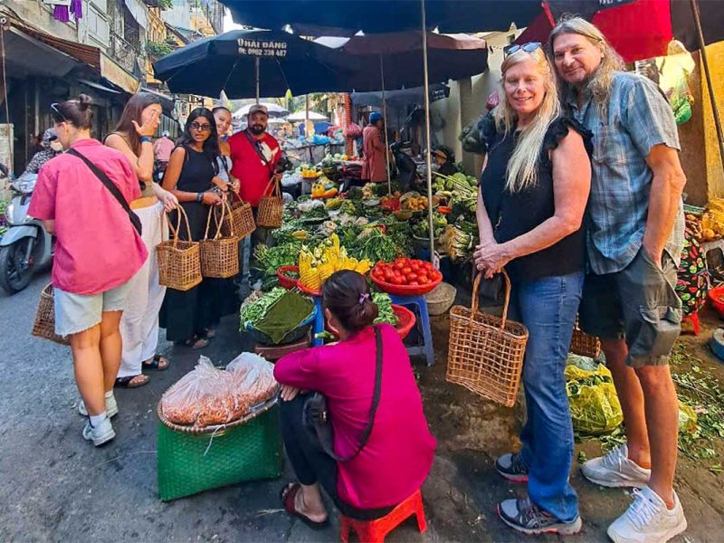 Couple standing together at a local market during a Hanoi cooking class tour