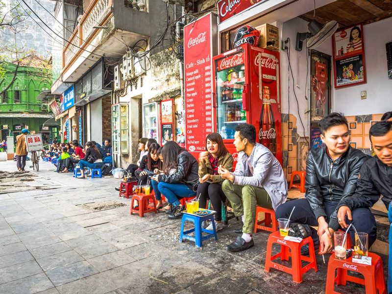 hanoi street coffee 1 Local Street Coffee Scene in Hanoi: Locals enjoy their morning coffee on colorful plastic stools at a traditional street-side cafe in Hanoi.