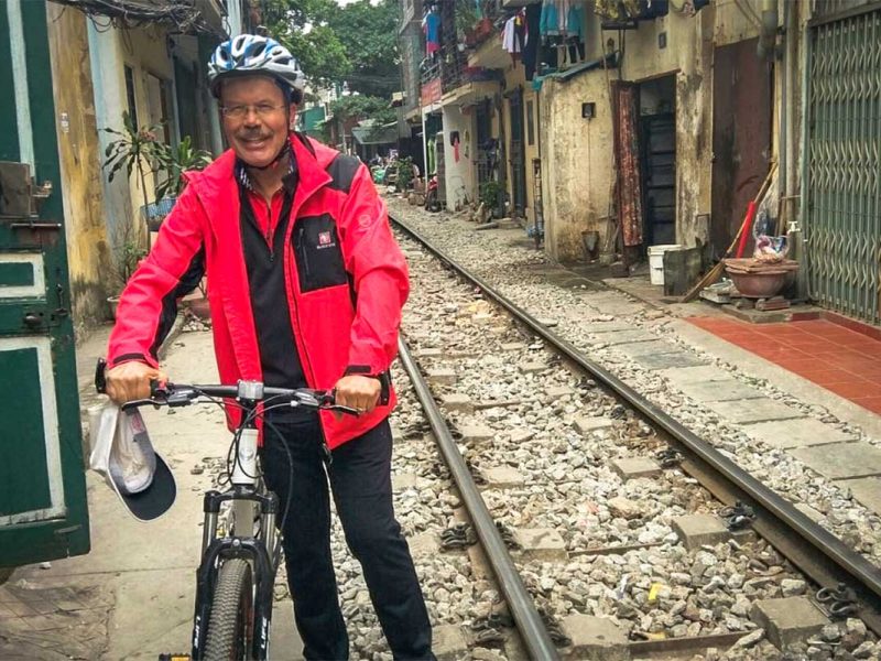 Man with bicycle standing on Hanoi Train Street during a biking tour