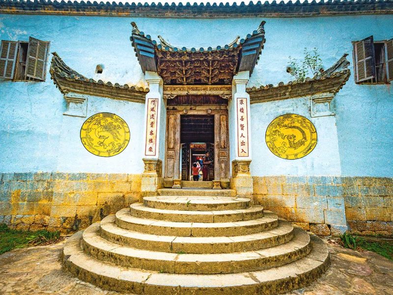 Entrance gate of the Hmong King Palace, featuring a sturdy stone wall with white and yellow circular symbols on both sides.