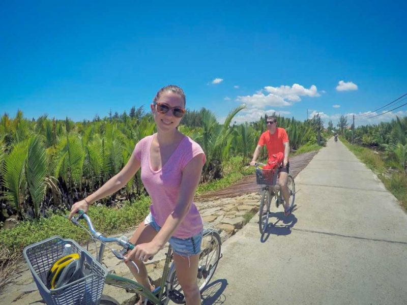 Cycling along a quiet countryside path lined with nipa palm trees on the Hoi An Kayaking & Cycling Tour