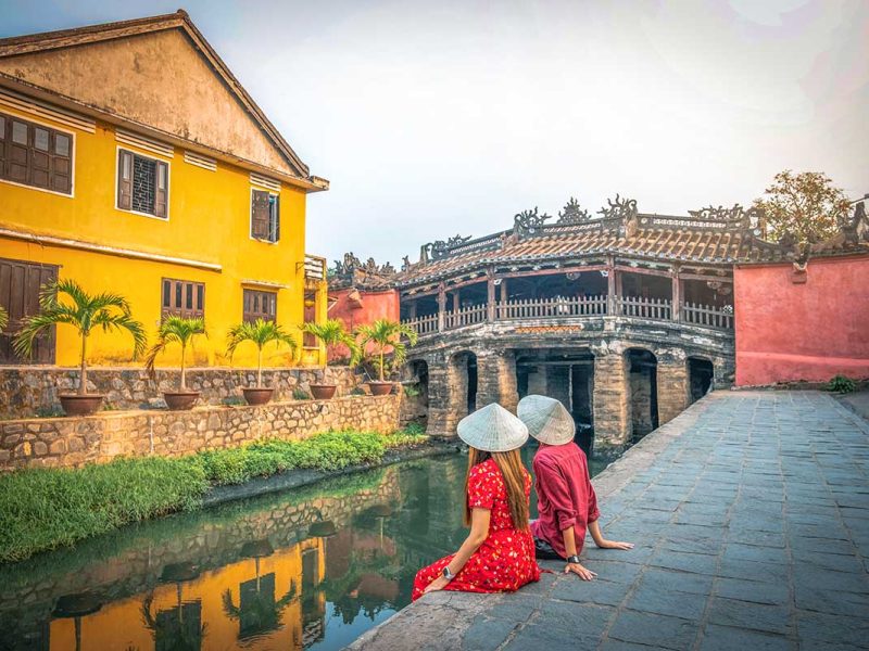 A couple sitting next to the Japanese Bridge in Hoi An for a romantic time in Vietnam