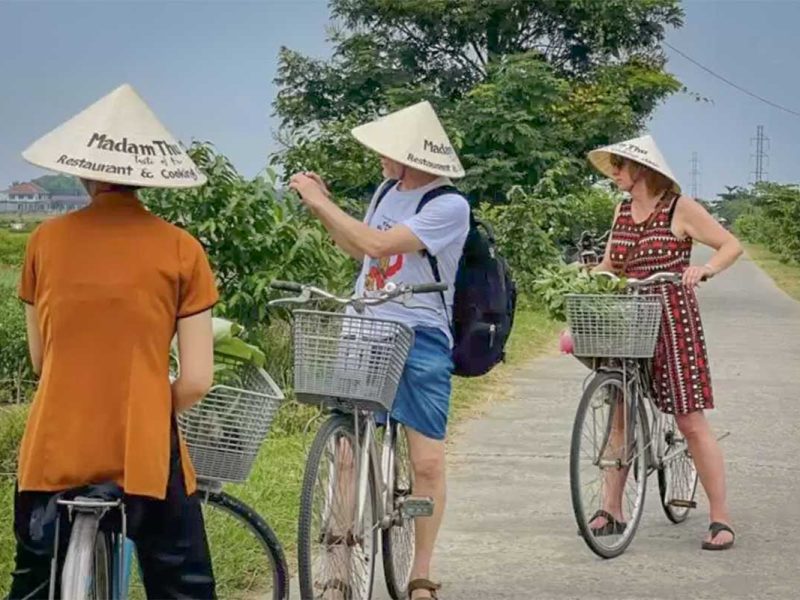 Travelers stopping to pick herbs and vegetables while cycling through Hue’s countryside villages.