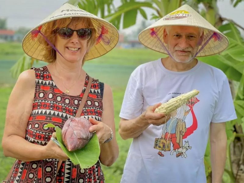 Tourists holding fresh produce from the fields during a hands-on Hue countryside farming tour.