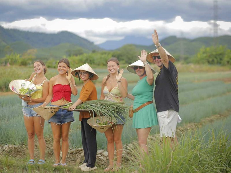 Visitors meeting local farmers and learning about vegetables in the fields on a Hue countryside tour.