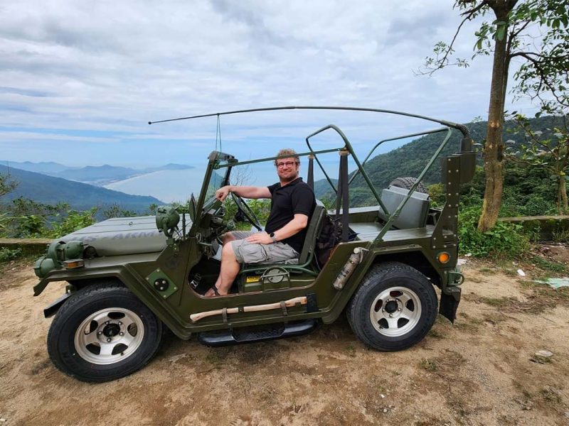 A tourist sitting in a military open jeep on the Hai Van pass that is part of a tour between Hoi An and Hue