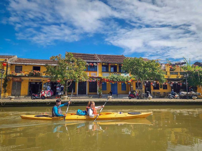 Kayaking along Hoi An’s riverfront with historic yellow houses lining the Thu Bon River