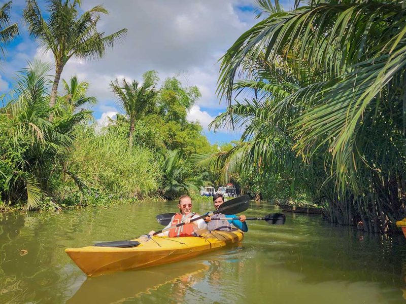 Kayaking next to dense nipa palms and sandy riverbanks on the Hoi An mangrove section of the tour