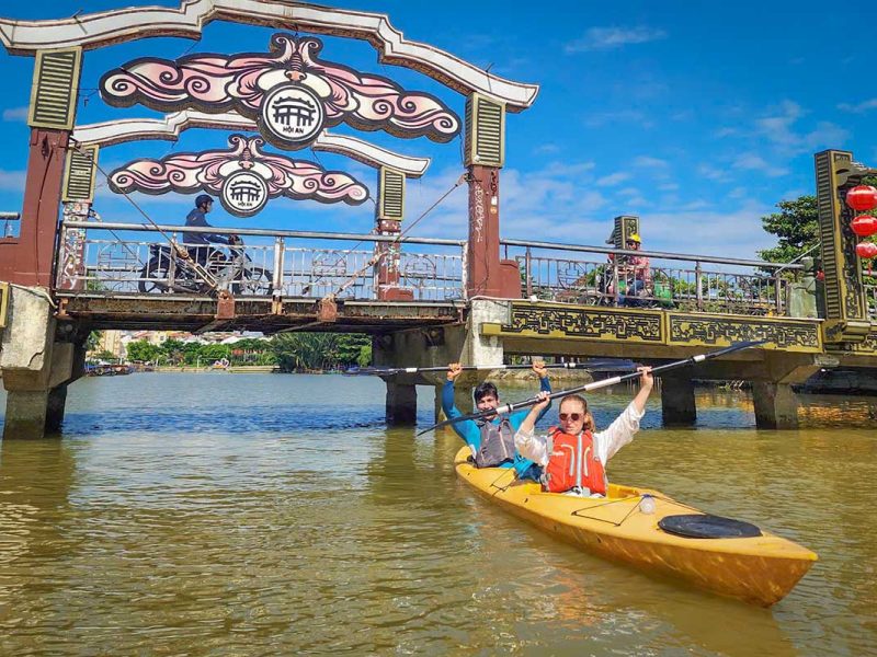 Kayaking under the decorative Hoi An bridge on the Thu Bon River during the Old Town & Mangrove Tour
