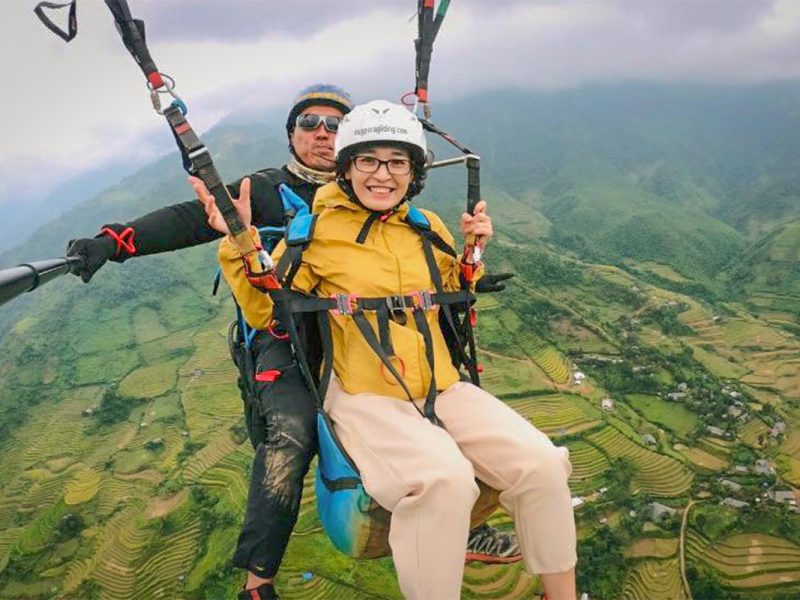 Linh Bui, manager at Local Vietnam, paragliding above the golden rice terraces of Mu Cang Chai in northern Vietnam — experiencing this iconic landscape firsthand as part of exploring new adventure and cultural tours for Local Vietnam.