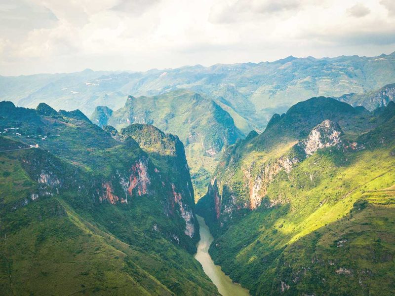 A breathtaking panorama from Ma Pi Leng Pass, with lush green mountains and the Nho Que River flowing far below.