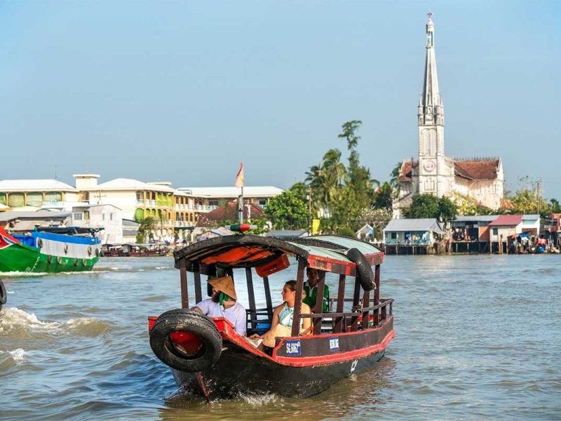A tourist couple is doing a motorized boat trip over the river in Cai Be, Mekong Delta
