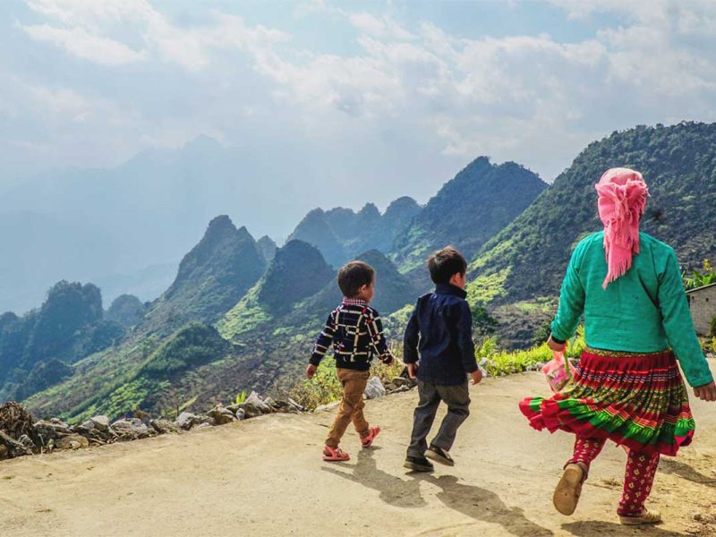 Ethnic minority woman and two children walking down a small mountain road in Meo Vac district, Ha Giang