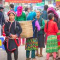 A group of ethnic women in colorful traditional clothing chatting at Meo Vac Market.
