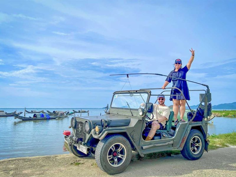 Traveler posing with a military jeep beside the fishing villages of Tam Giang Lagoon during the Hai Van Pass tour from Hue.