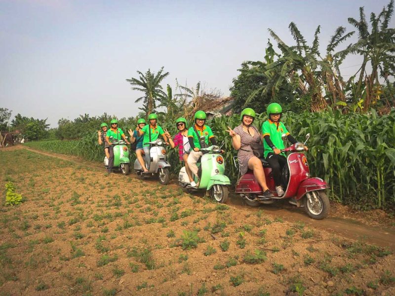 Travelers riding Vespa motorbikes through Hanoi’s countryside with local guides on a motorbike tour