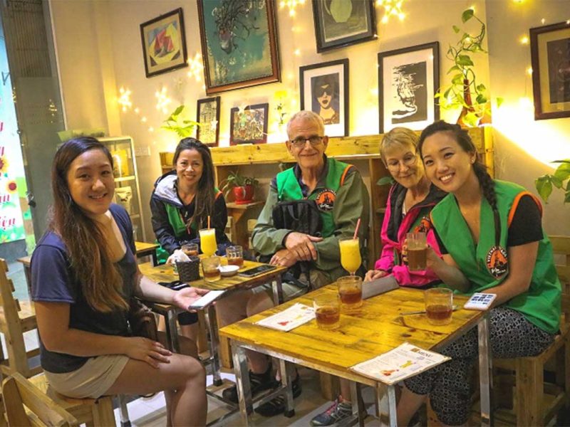 Motorbike tour group relaxing with drinks in a local Hanoi café with their Vespa guides