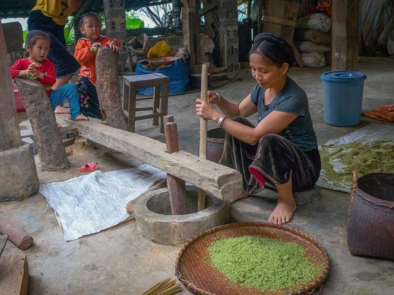 Mu Cang Chai Hmong family preparing green rice (com) inside a traditional wooden stilt house